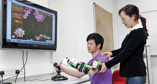 胡博士指导患者利用互动电脑游戏训练其手部功能。