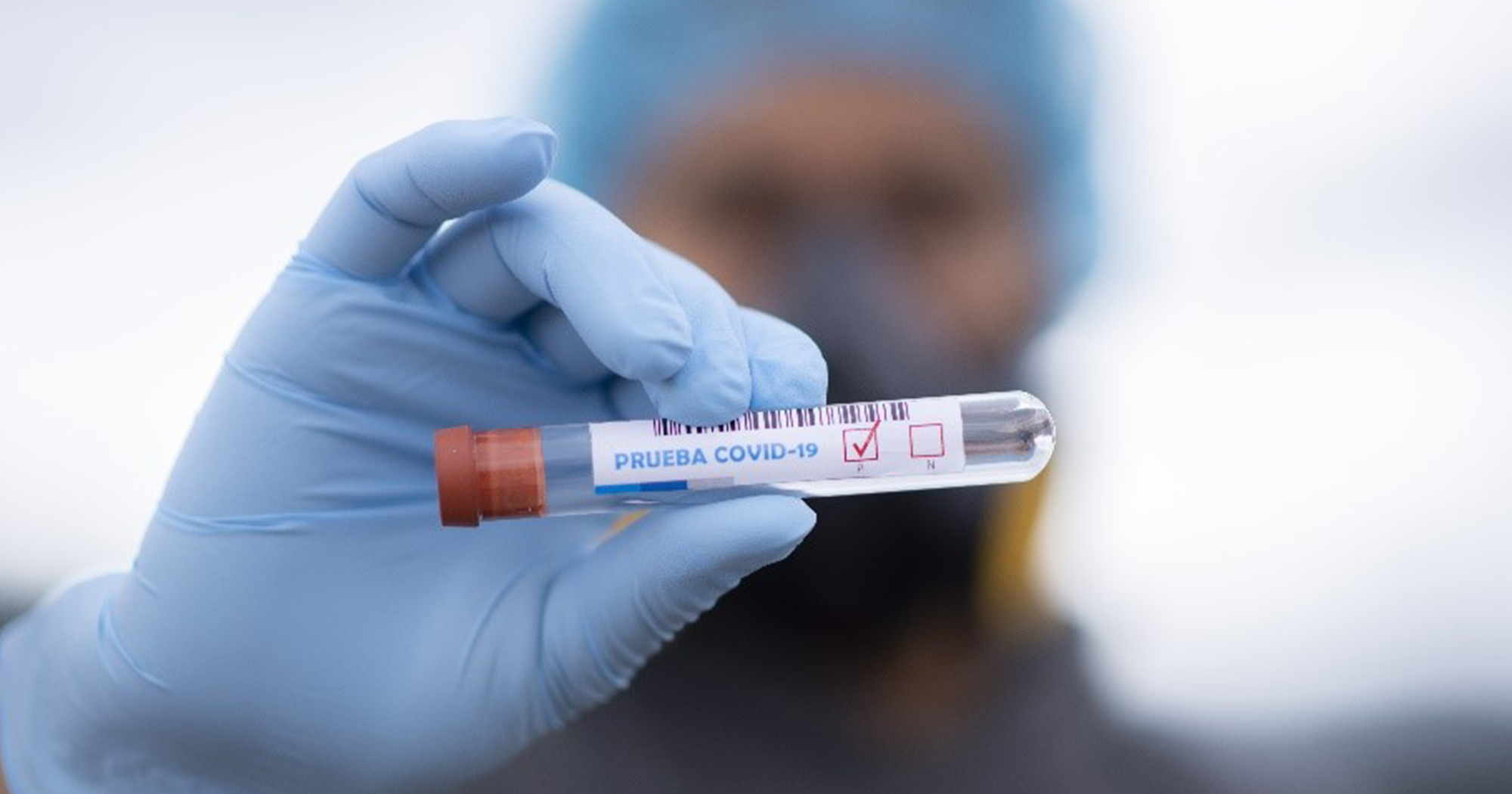A hand of doctor in a protective suit hold a covid-19 blood sample tube