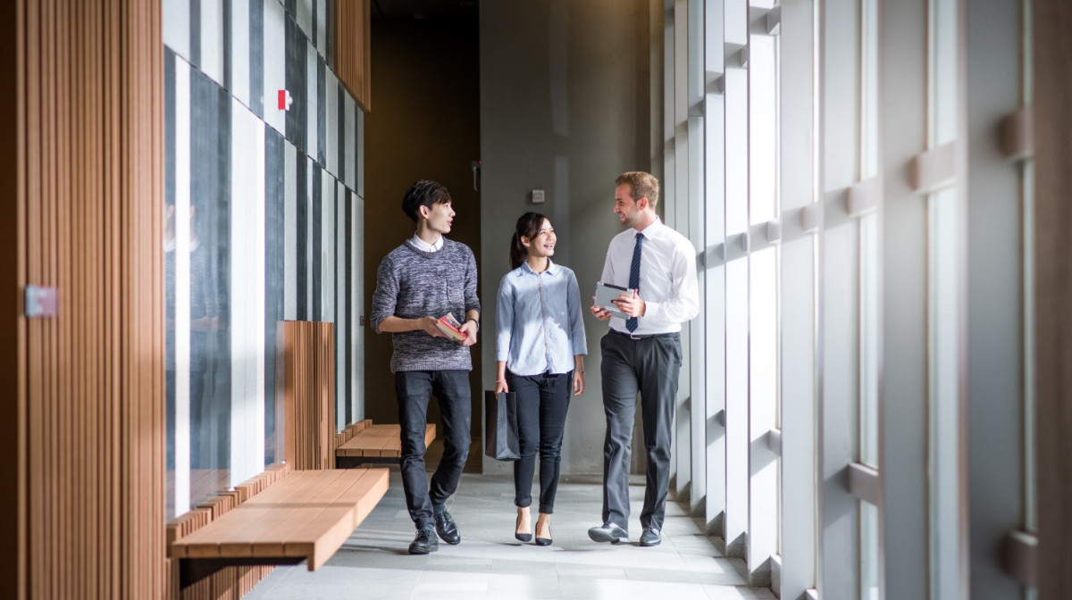 Asian and foreign students chatting while walking in corridor