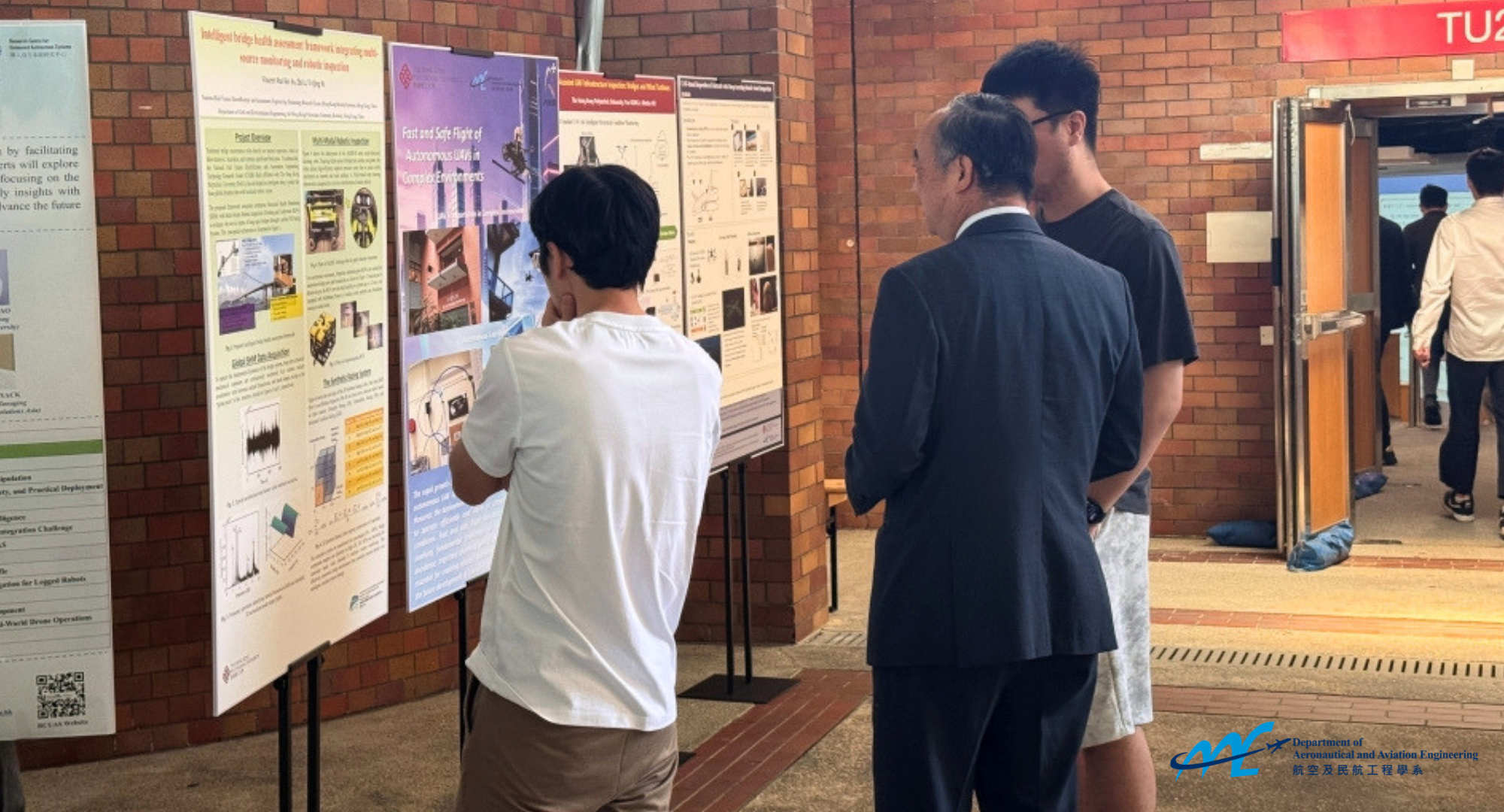 Prof. Wen Chih-Yung, Director of the RCUAS, discusses research ideas with students during the poster session at the 2nd Research Workshop of RCUAS.