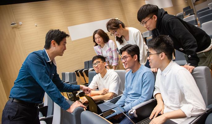 teacher in blue shirt talk to 6 students