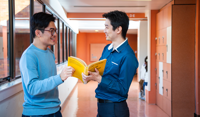 teacher in blue shirt and student in blue tee talk in the corridor
