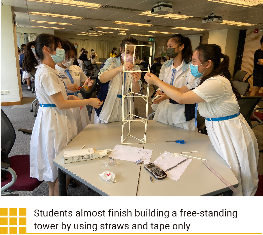 Students almost finish building a free-standing tower by using straws and tape only