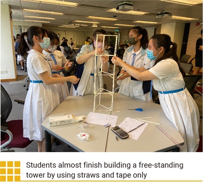 Students almost finish building a free-standing tower by using straws and tape only