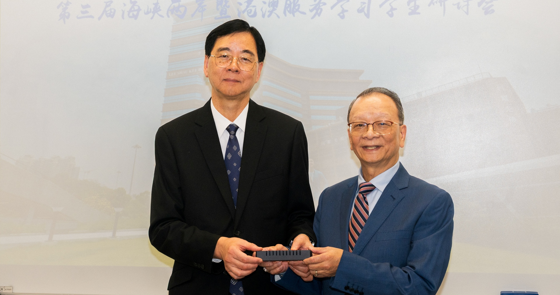 理大协理副校长（本科生课程）石丹理教授（左）致送纪念品予田家炳基金会代表谢国强博士（右）。