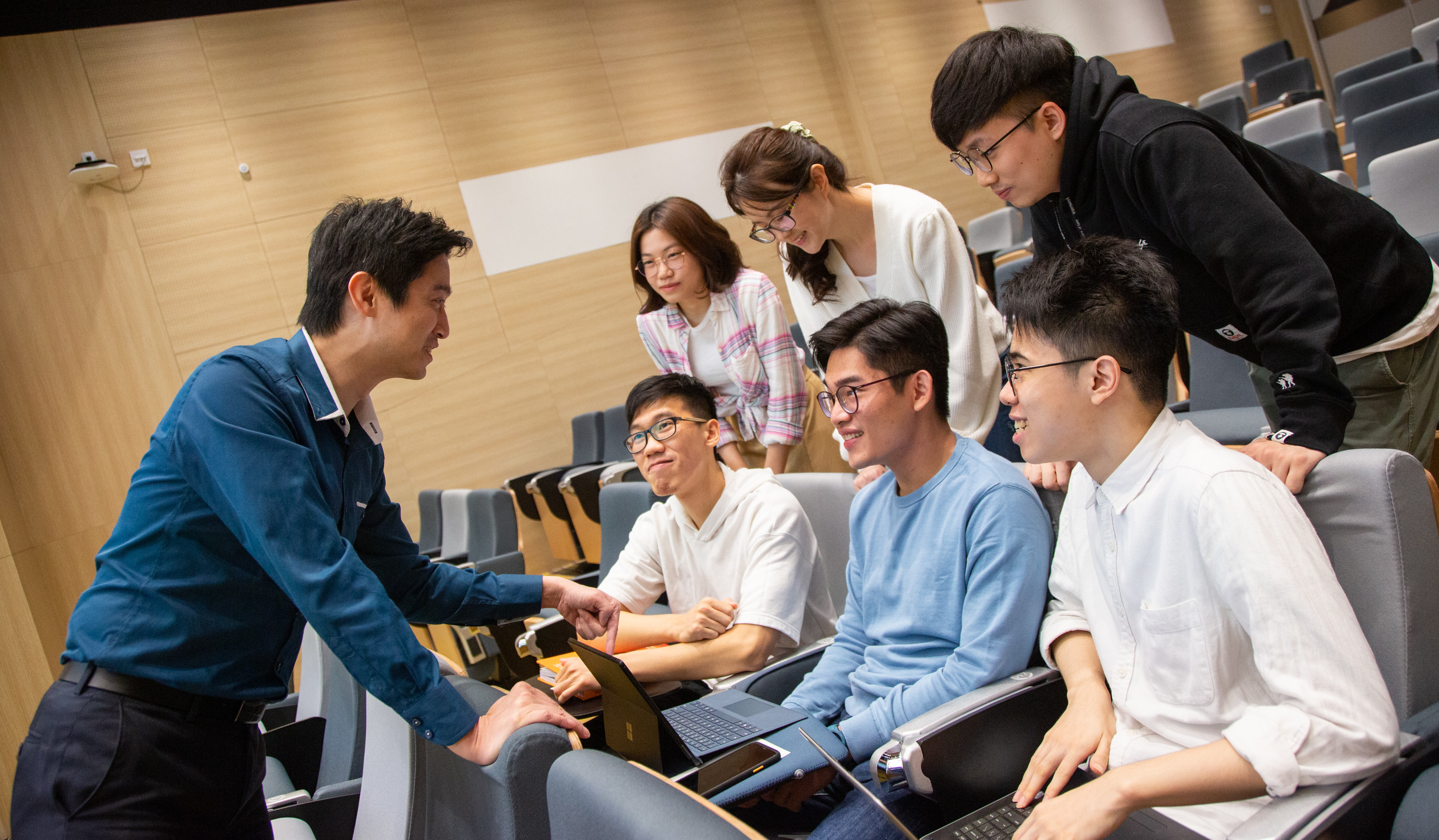 teacher in blue shirt talk to 6 students