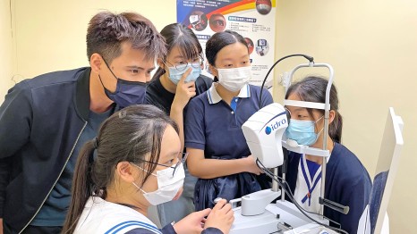 理大眼科视光学院陈家贤博士（左）指导来自弘立书院、港大同学会书院、宝血会上智英文书院及新界乡议局元朗区中学的同学，进行一项关於干眼症的研究。