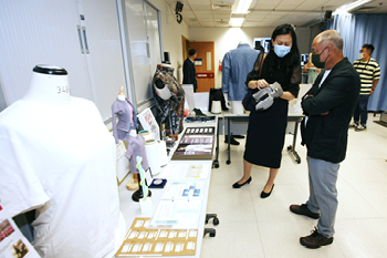 智能可穿戴系統研究院李鸝教授(左)向李寧博士展示理大的智能保暖科技。