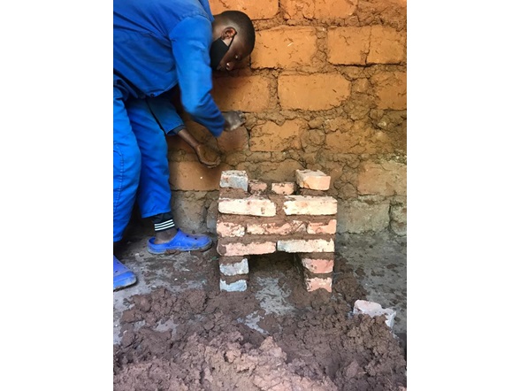 Local Rwandan youth constructing rocket stoves for households