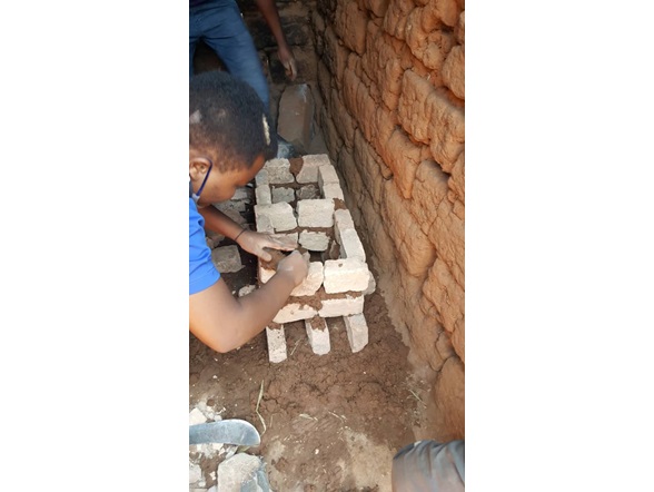 Local Rwandan youth constructing rocket stoves  