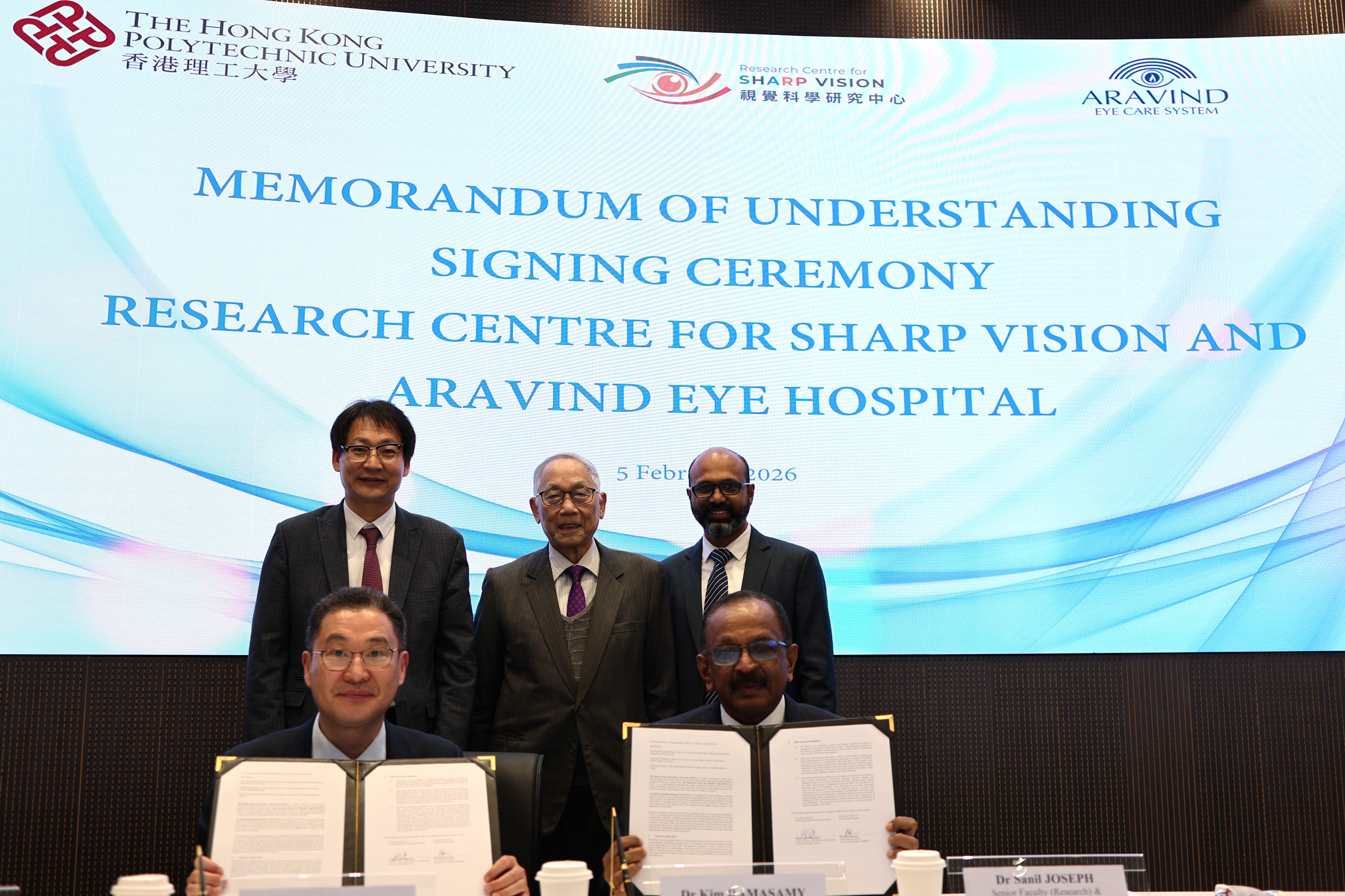 Prof. He Mingguang (front row, left), Director of the Research Centre for SHARP Vision at PolyU, and Dr R. Kim (front row, right), Chief Medical Officer & Senior Consultant at Aravind Eye Hospital, sign the MoU during the ceremony. With witness of Professor Wang Zuankai (back, left), Associate Vice President (Research) of PolyU and Dr Joseph Sanil (back, right), Senior Faculty and Health Services Research Consultant from Aravind Eye Hospital.
